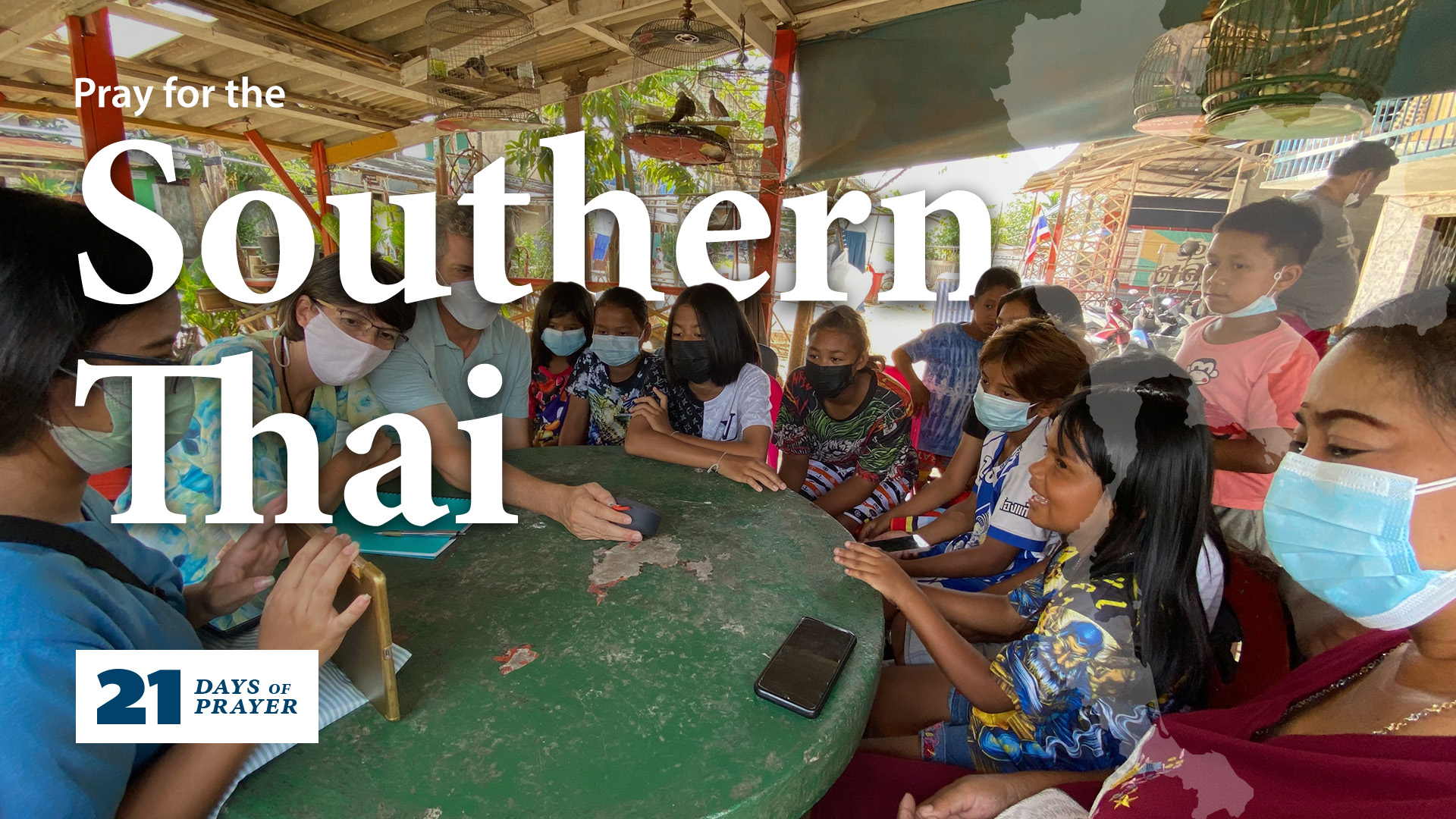 A number of youth sit around a round table, looking at what the teacher is presenting. The text reads 